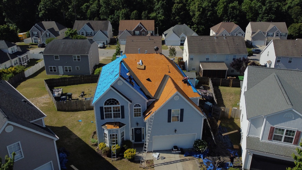 Crew laying synthetic underlayment after plywood inspection