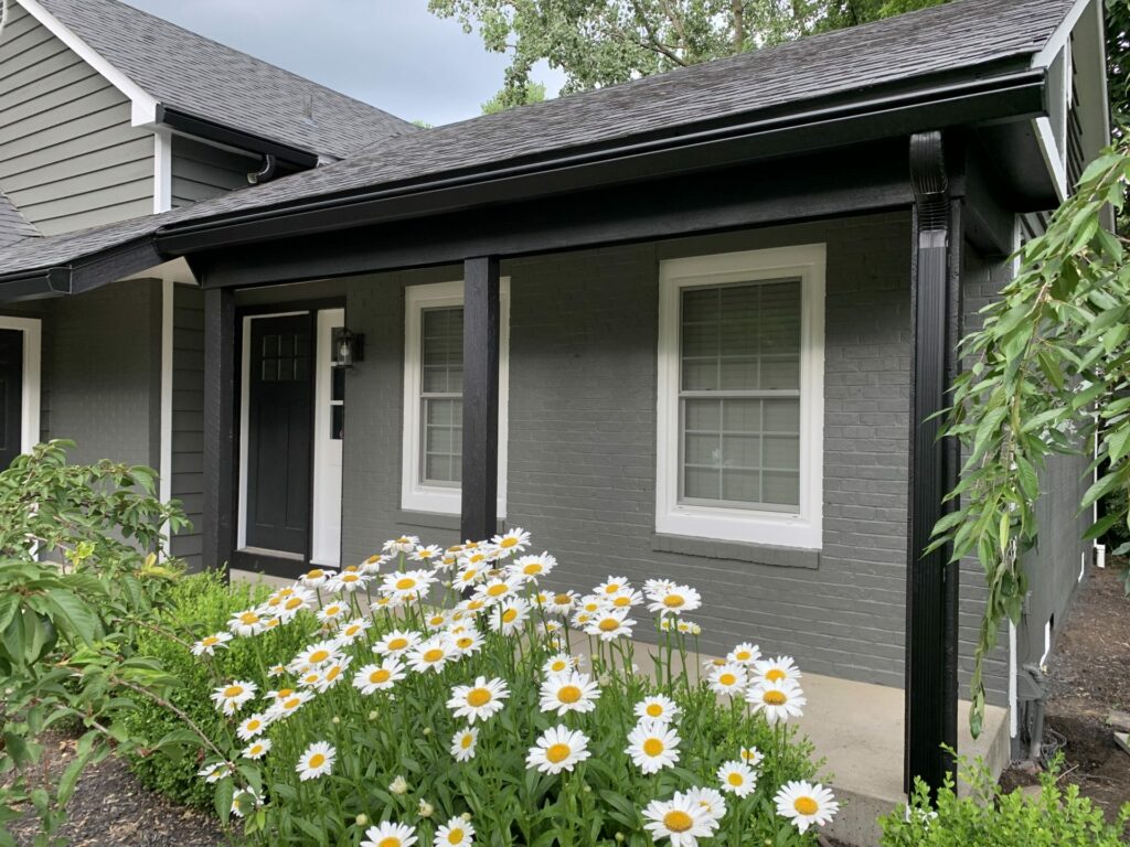 Black seamless gutter system with downspout integrated into the porch design