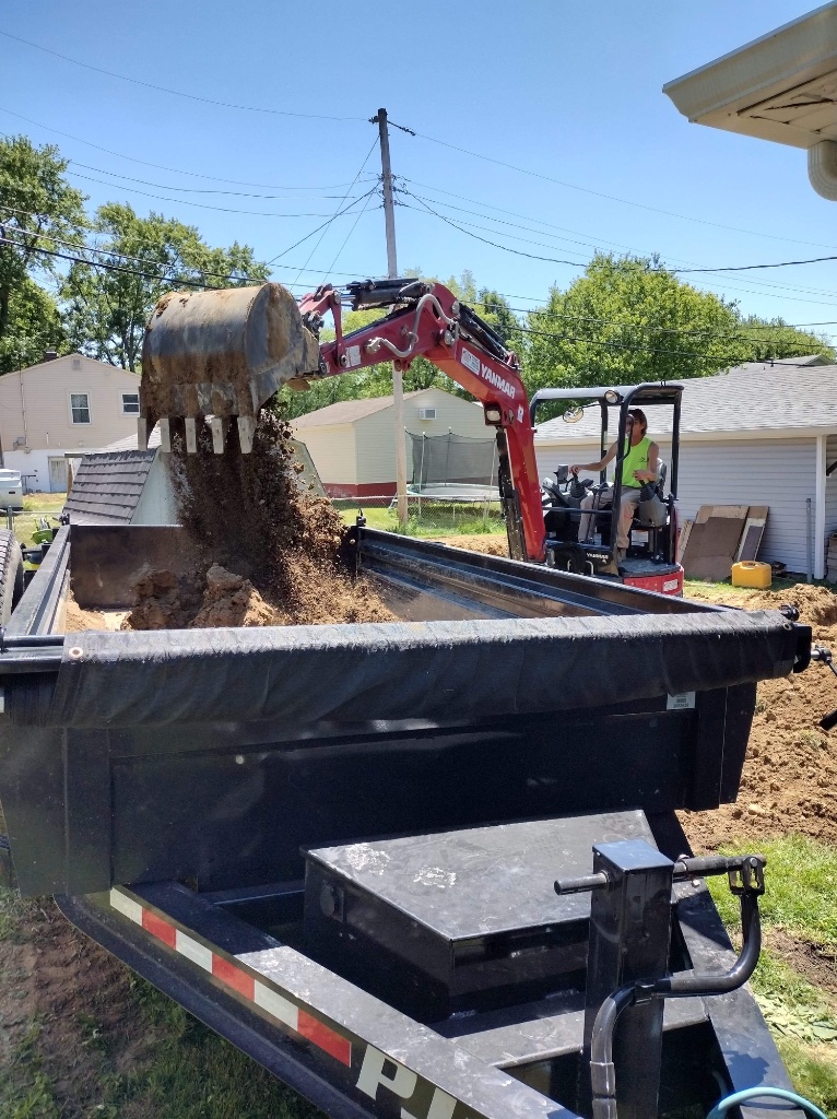 Mini-excavator dumping into a trailer
