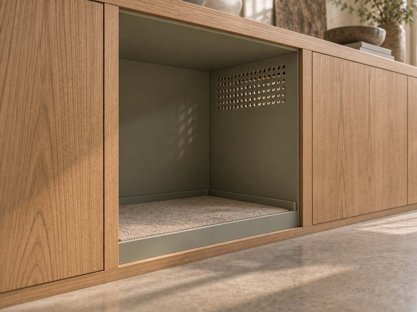 Close-up of a doorless built-in timber alcove for a dog: sealed edge-banded opening, perforated ventilation panel high in the grey-green side wall, and a recessed washable liner tray.