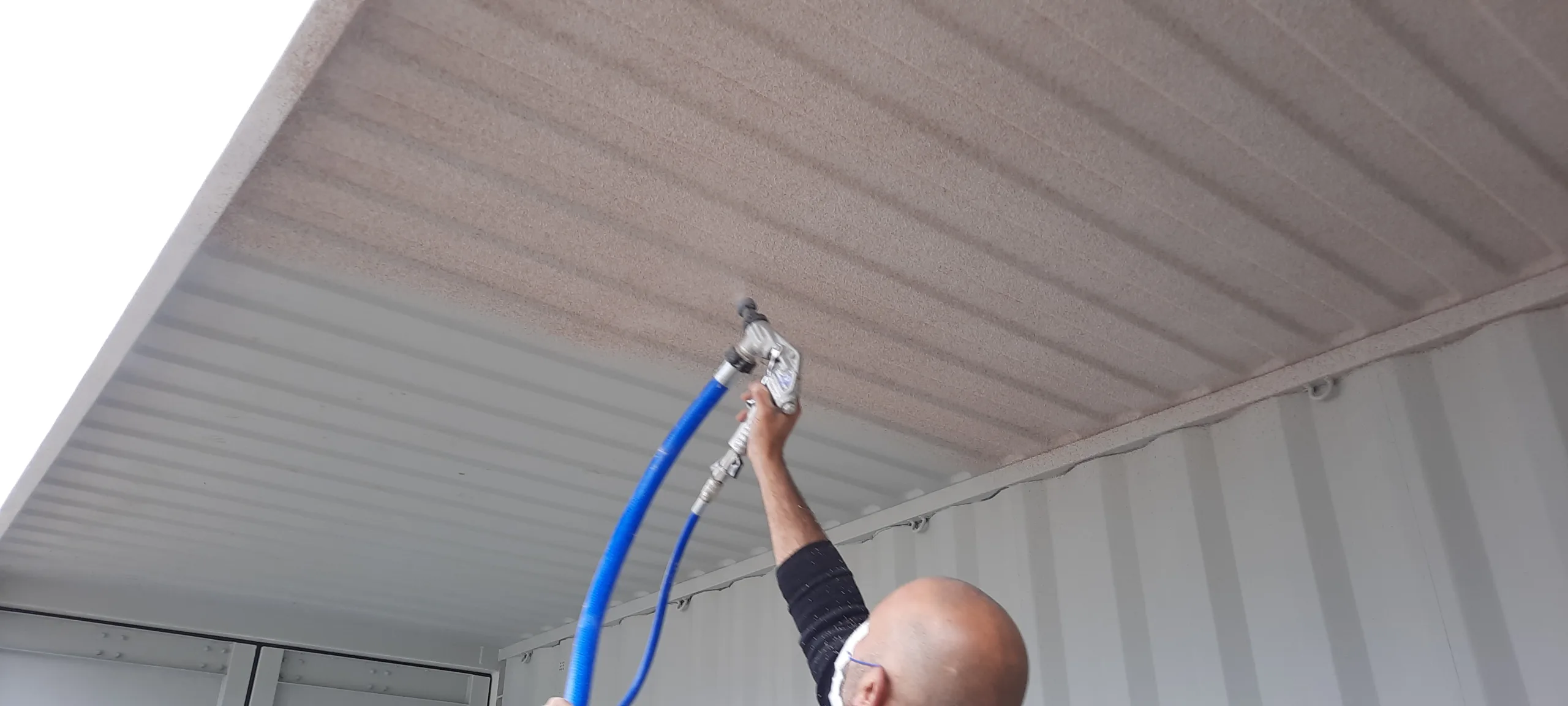 VIPEQ applicator spraying thermal cork insulation onto shipping container ceiling