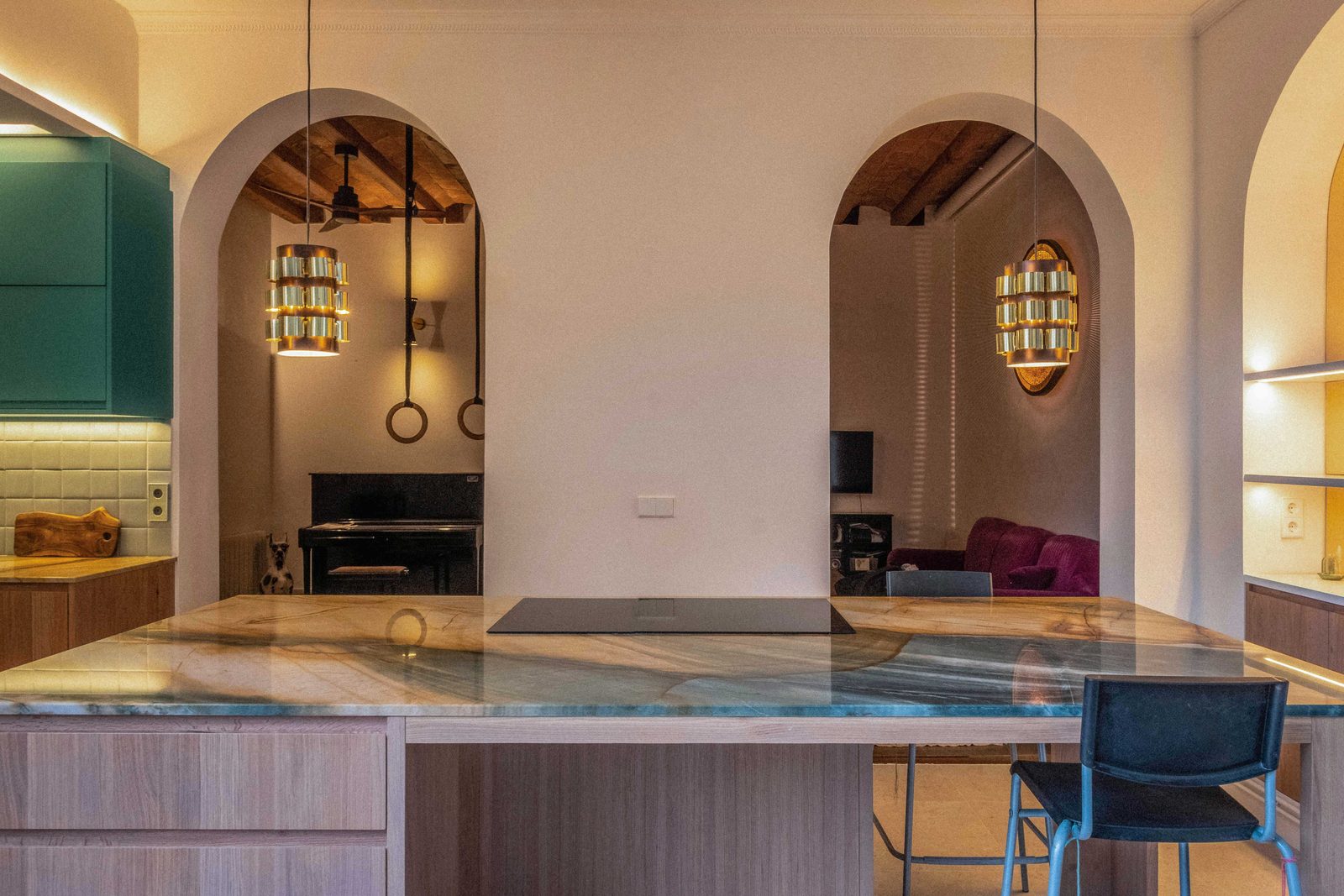 Cocina reformada con arcos, isla de piedra y muebles verde azulado