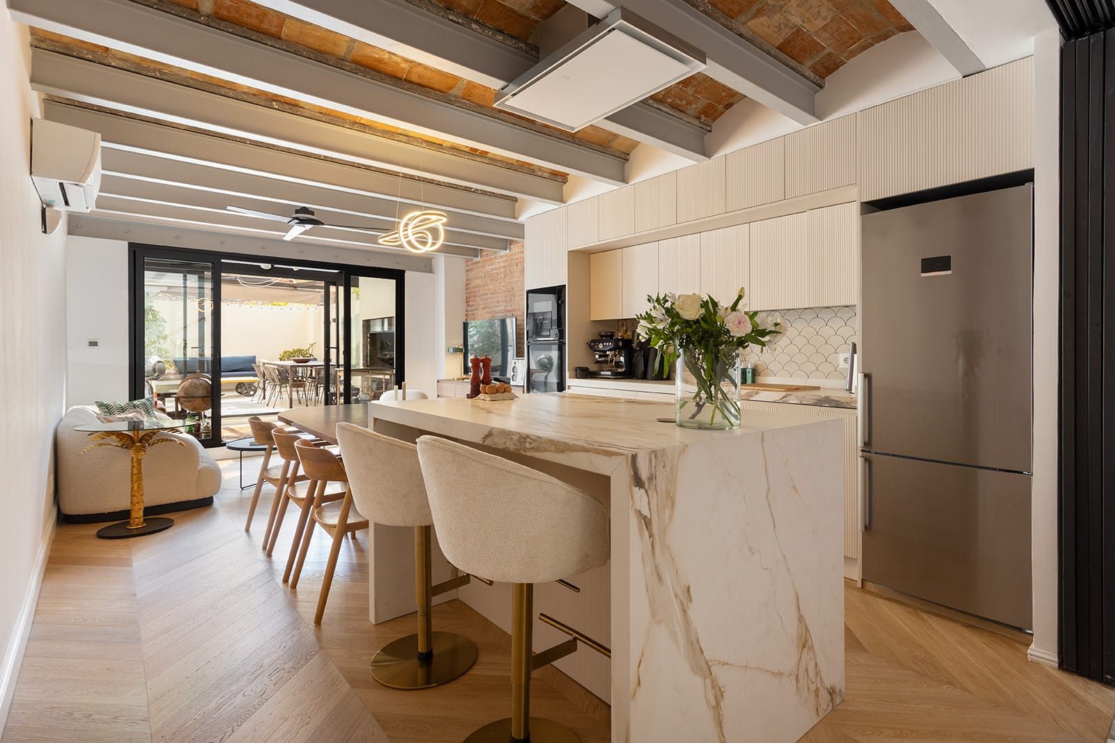 Cocina abierta con isla de mármol y vigas vistas