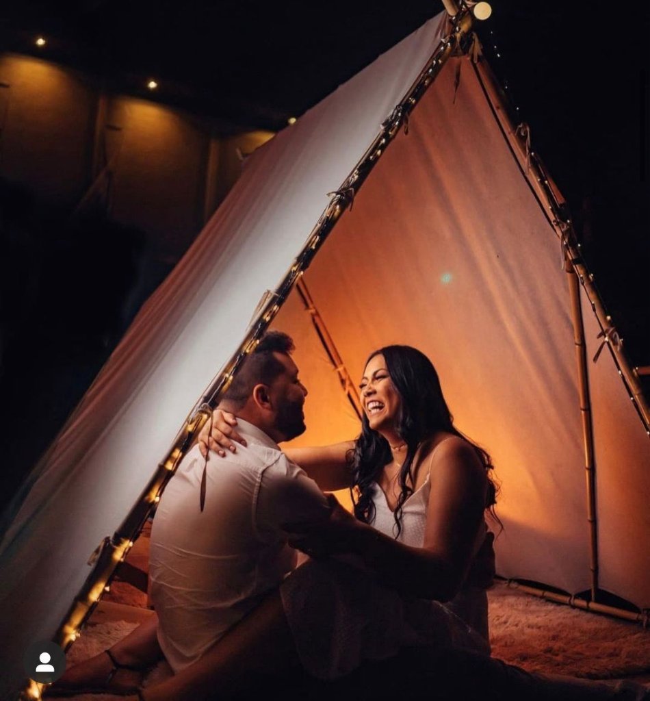 Casal rindo dentro da tenda iluminada