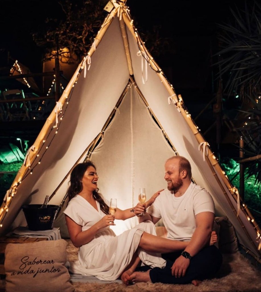 Casal brindando dentro de tenda iluminada