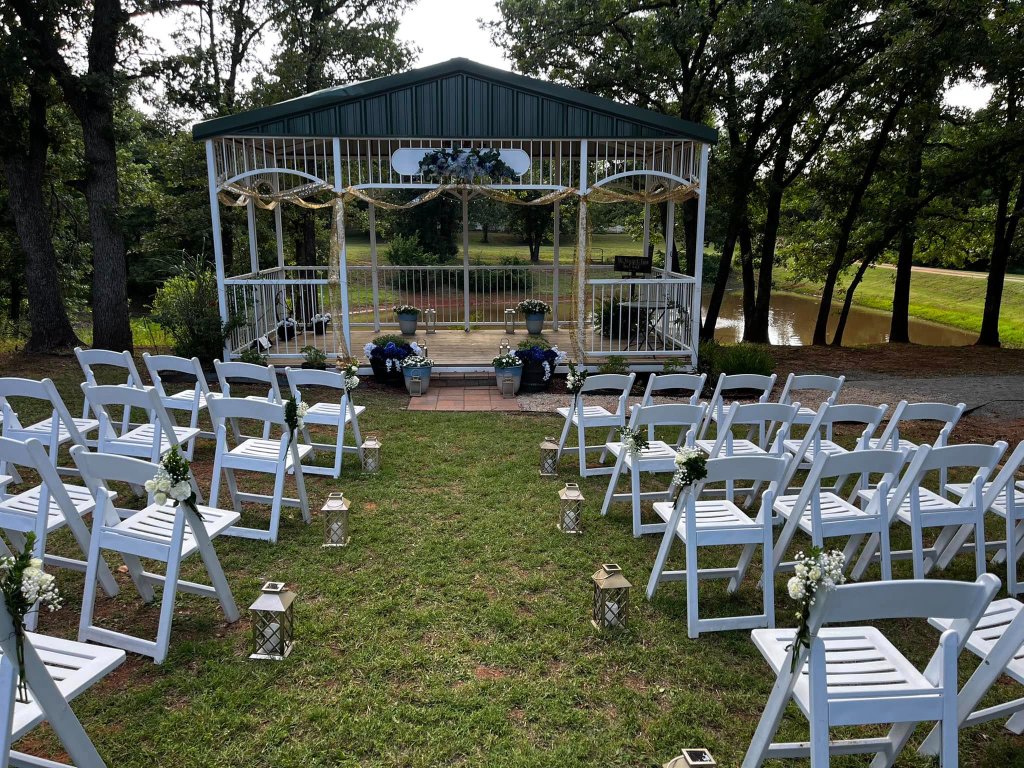 Wedding ceremony setup with white chairs and pavilion