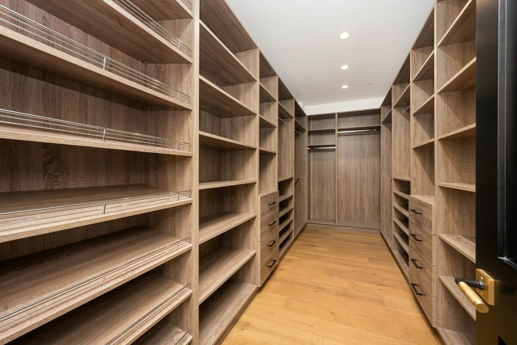 Full walk-in wardrobe in brushed oak — floor-to-ceiling shelving, hanging rods and shoe trays. Every category of your wardrobe has its exact place.