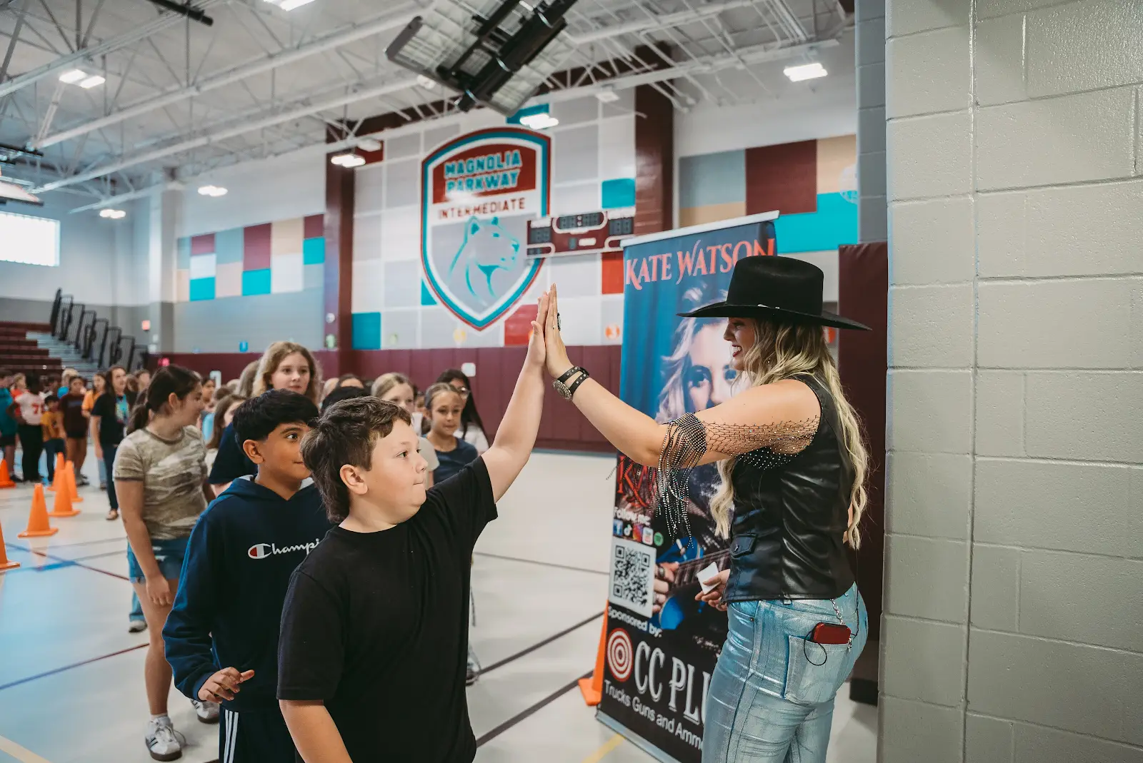 Kate Watson high-fiving a student during a school performance