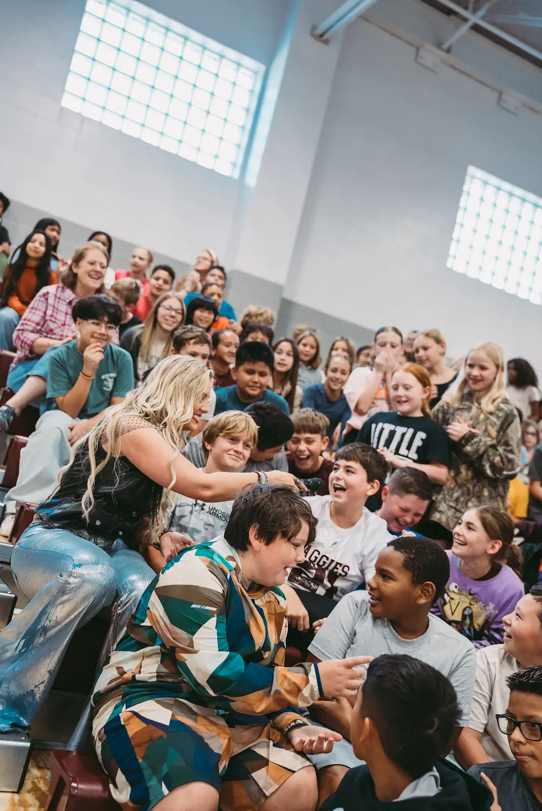 Kate Watson kneeling on the bleachers interacting with students