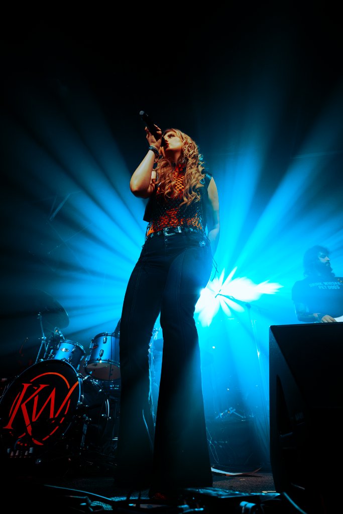 Kate Watson performing with blue stage lights