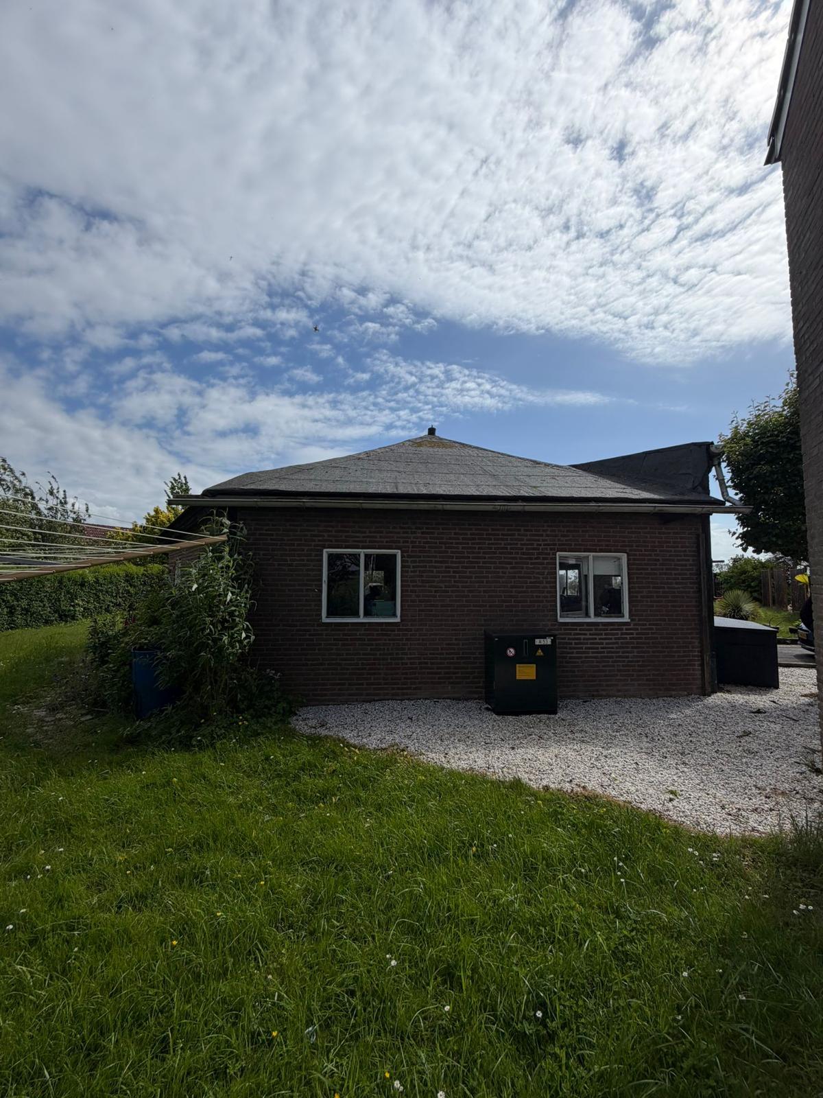 Zijgevel van het bijgebouw met grindpad en omringende tuin — YMD Bouw
