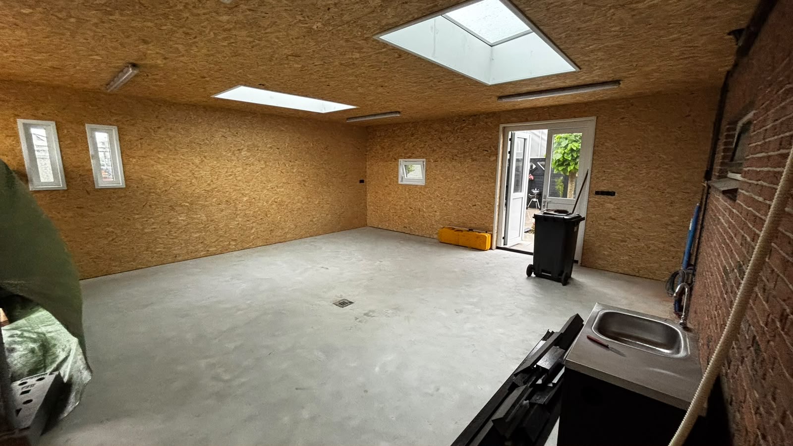 Interieur van de nieuwe garage met OSB-wanden, lichtstraten en betonvloer
