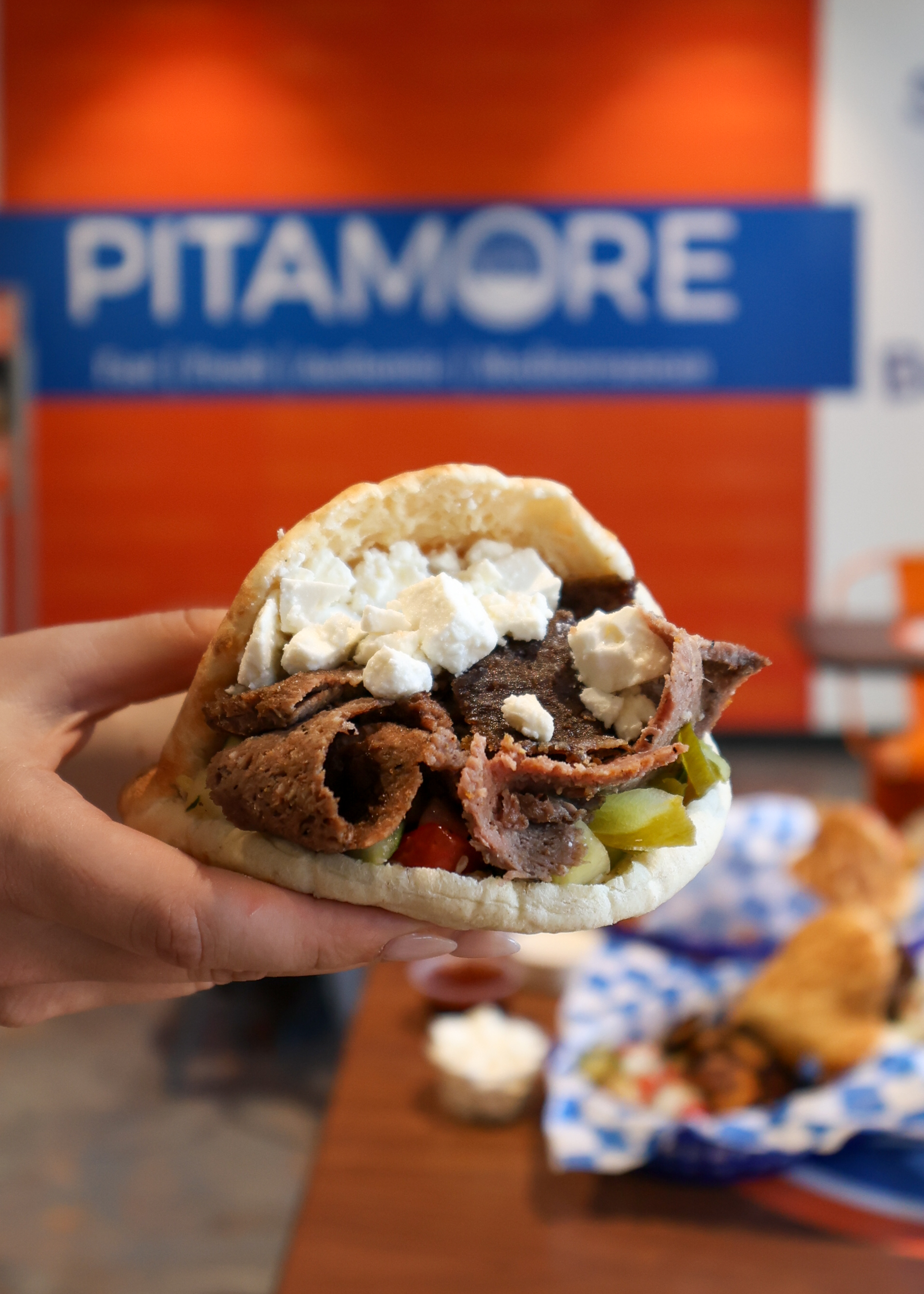 Shawarma pita with feta held up, Pitamore
