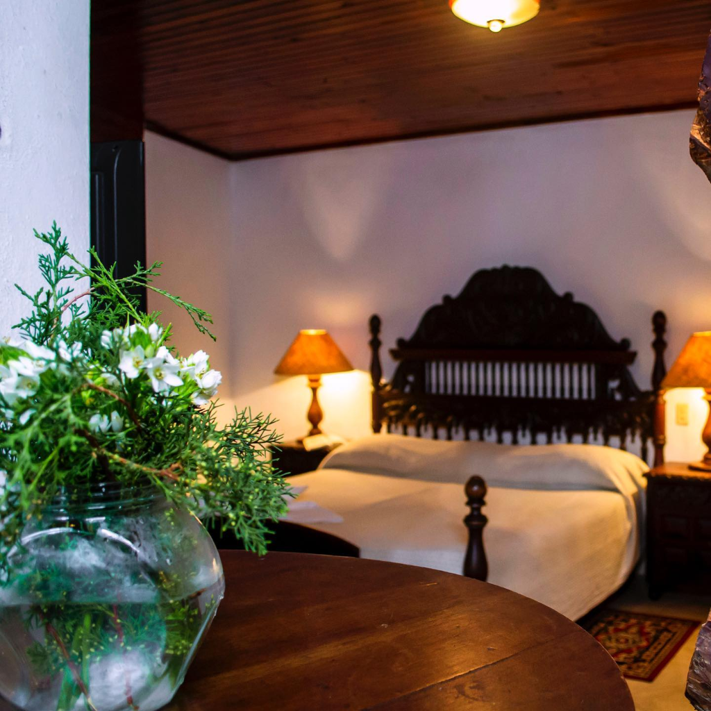 Habitación con cama tallada y flores blancas