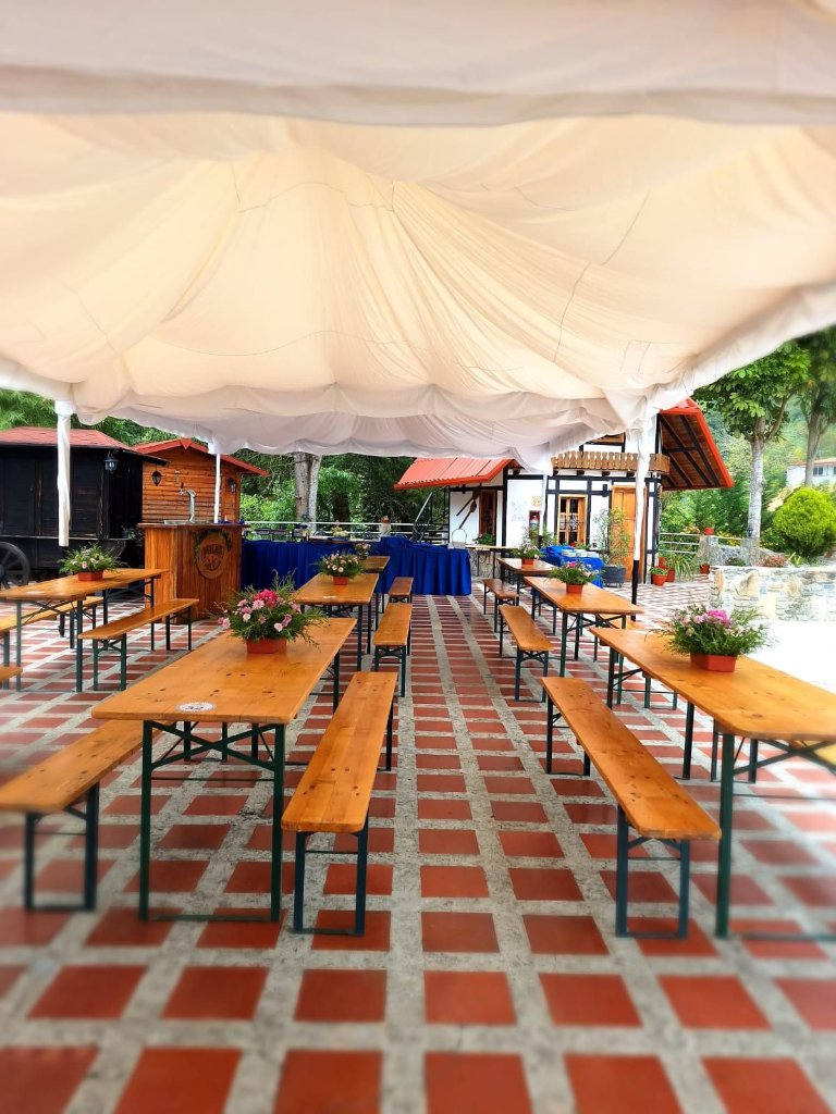 Terraza con mesas tipo picnic bajo carpa
