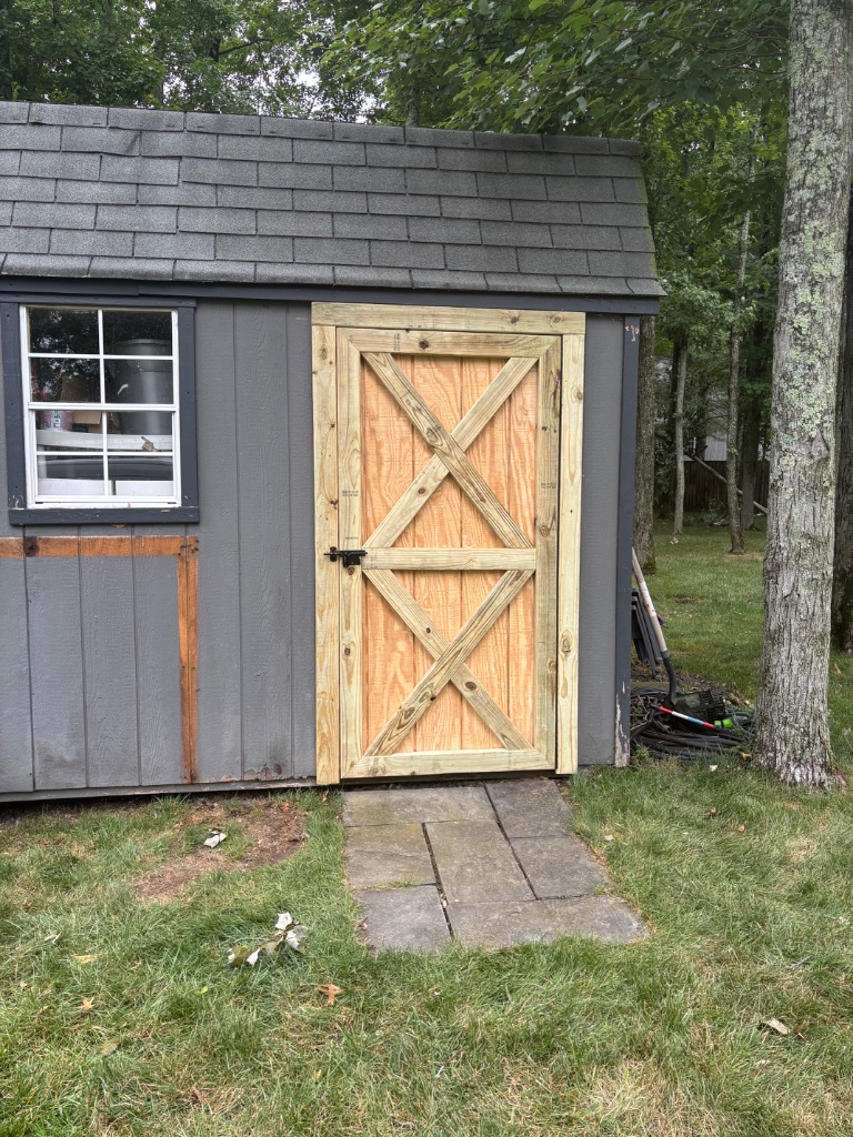Shed with newly installed natural wood barn-style door
