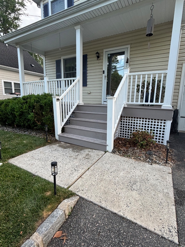 Front entry porch with grey wooden steps and white railings