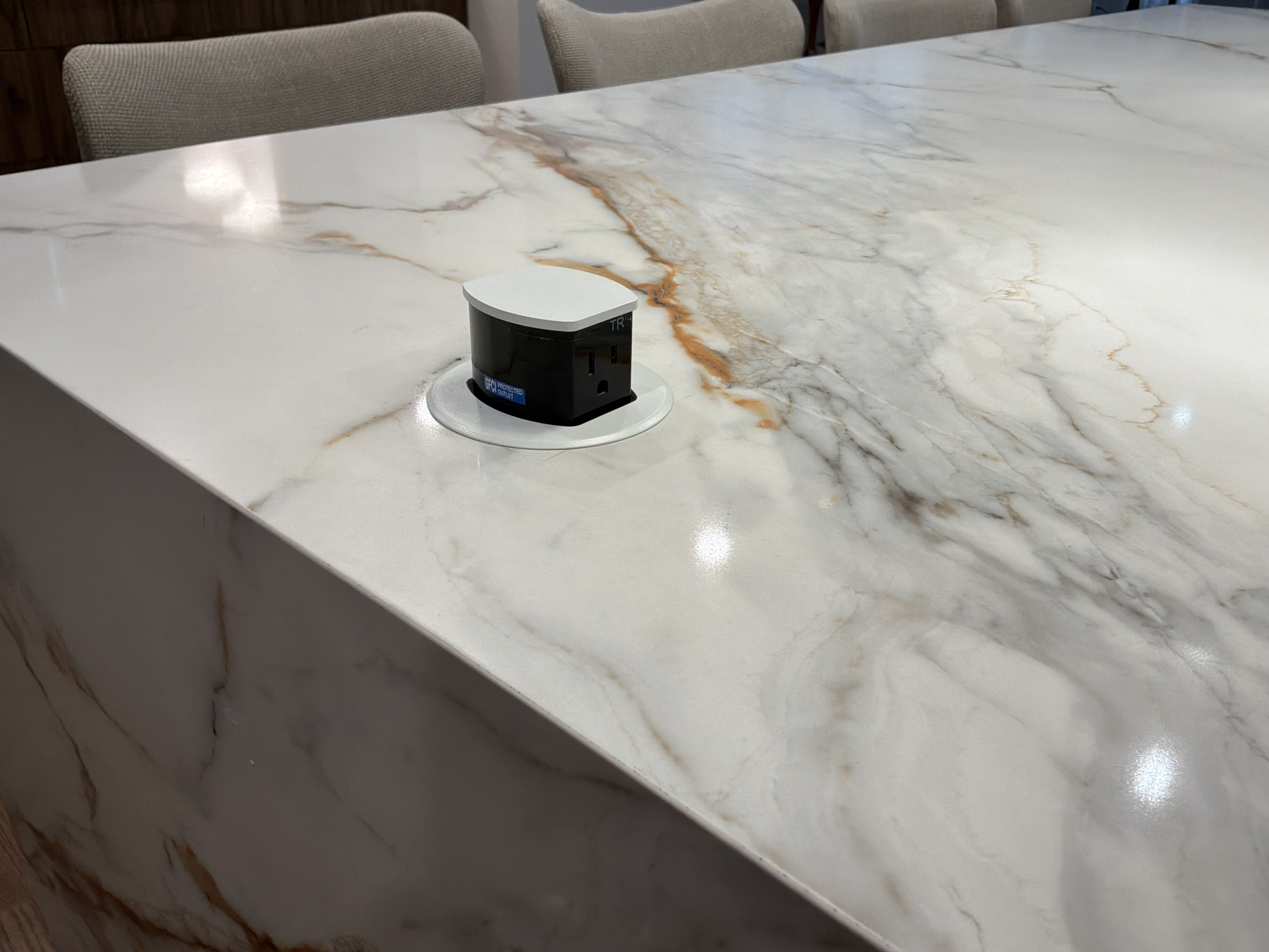 White and gold marble island countertop with pop-up outlet detail