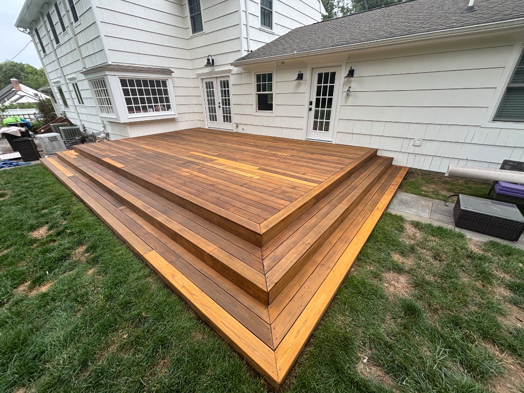 Multi-tiered wooden deck with steps wrapping around the house