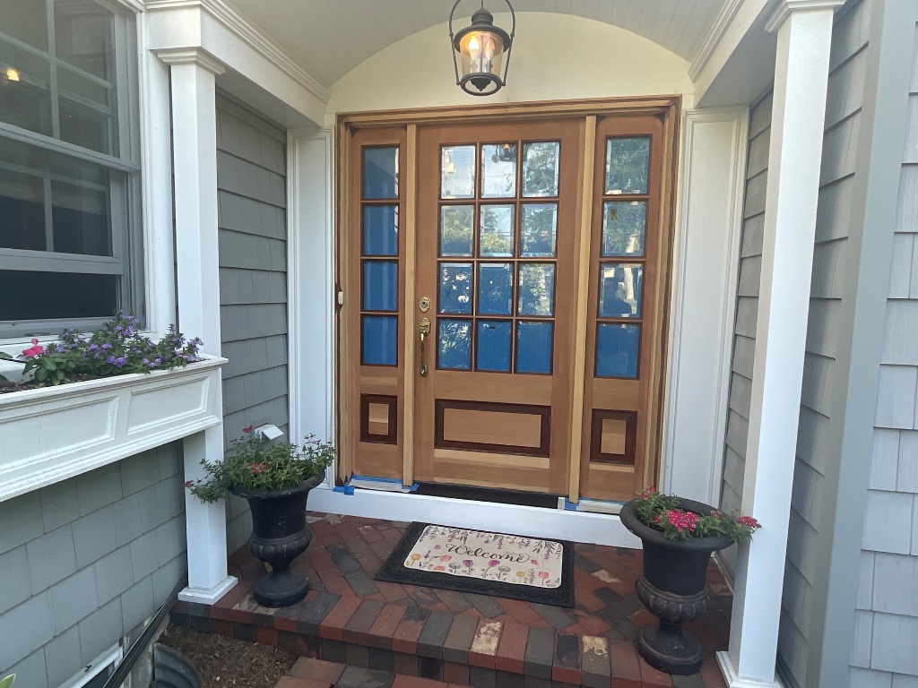 Front entry door refinishing in progress with painter tape