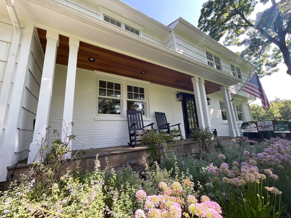 Front porch with stone floor, rocking chairs, and American flag