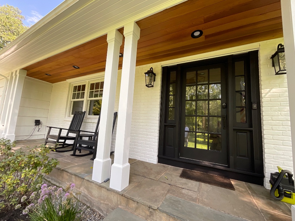 Covered front porch with painted brick, wood ceiling, and rocking chairs