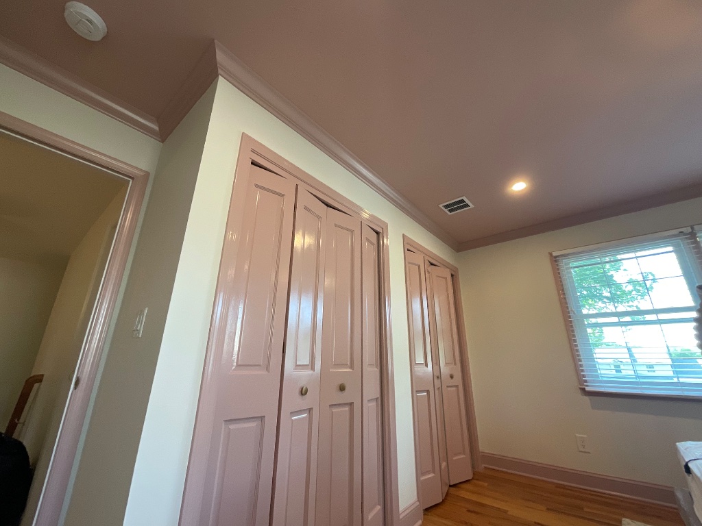 Interior room with cream walls, dusty rose trim, and bifold closet doors