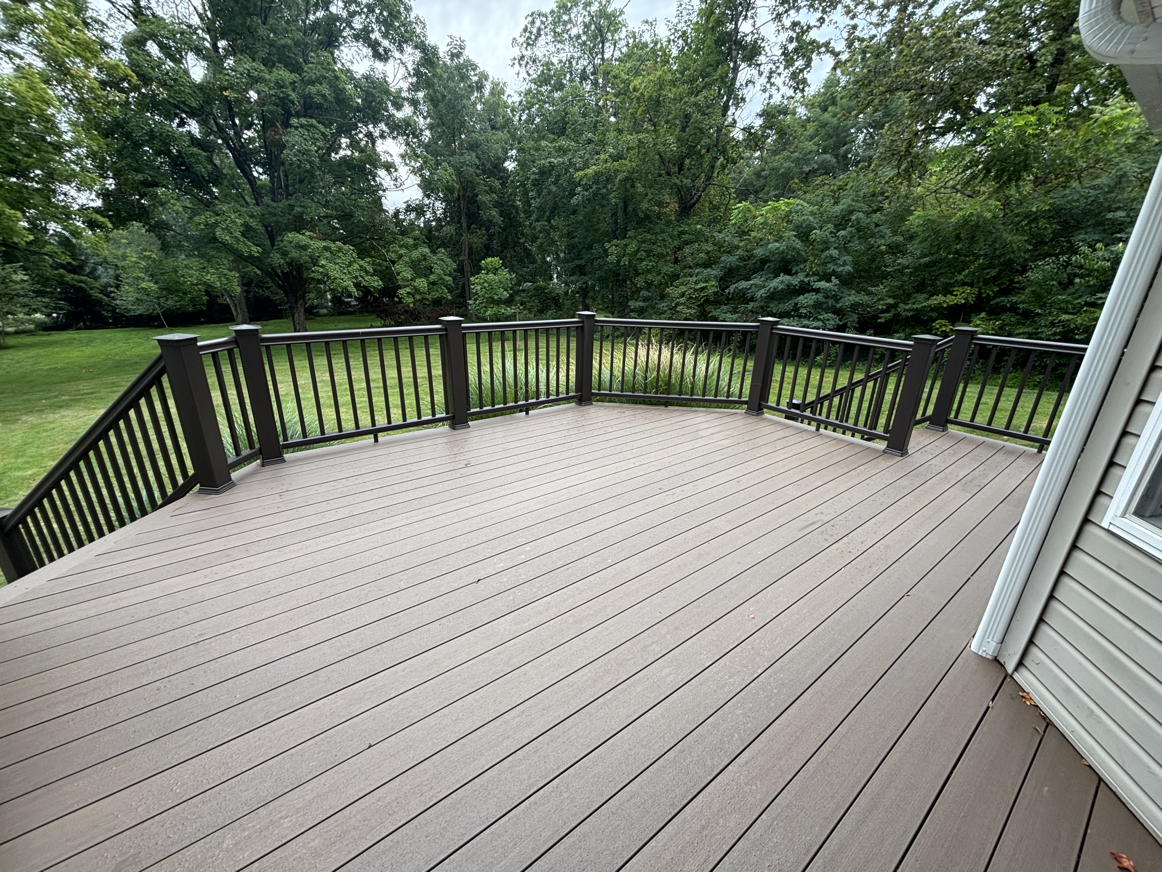 Multi-level composite deck with dark railing overlooking the lawn