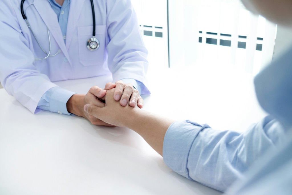 A physician holding a patient's hand in a gesture of care