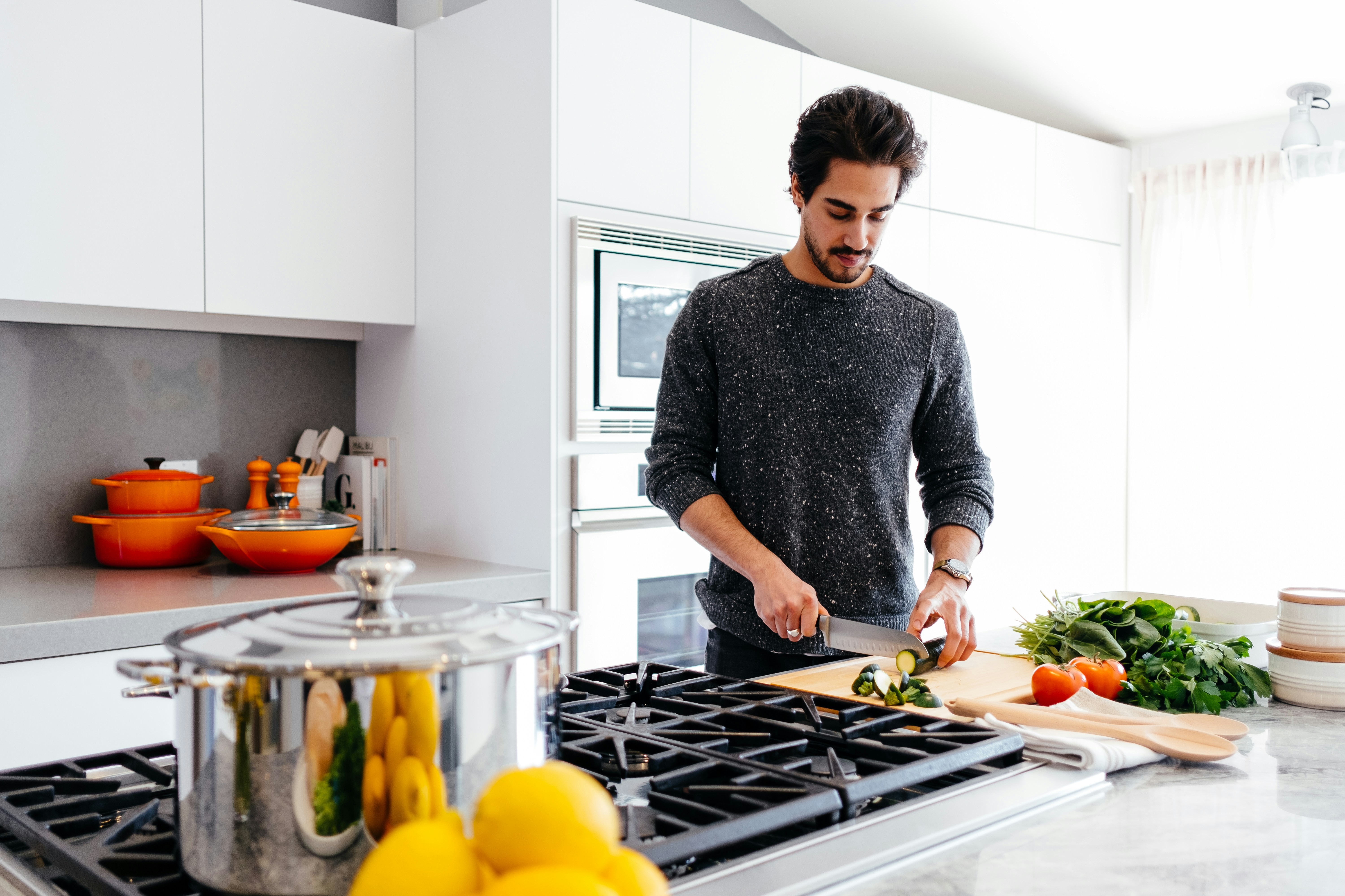 A man slicing vegetables in a bright modern kitchen