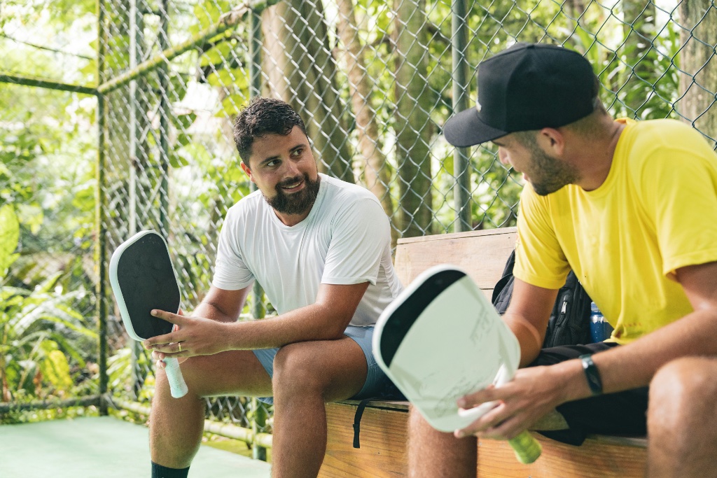 Two men talking on a pickleball court