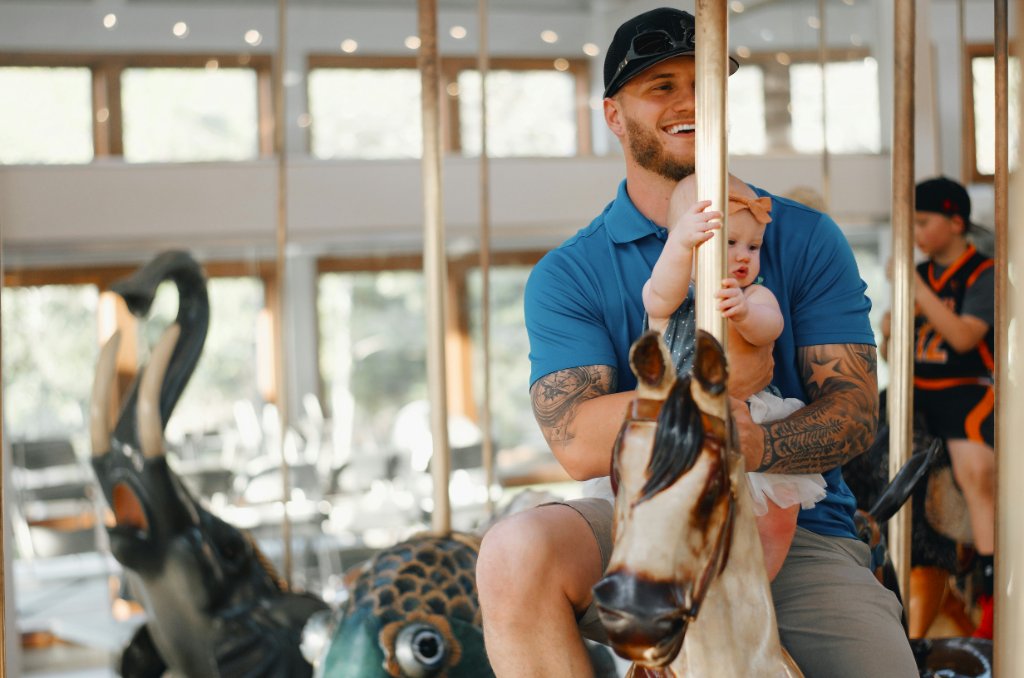 A father smiling with his baby on a carousel