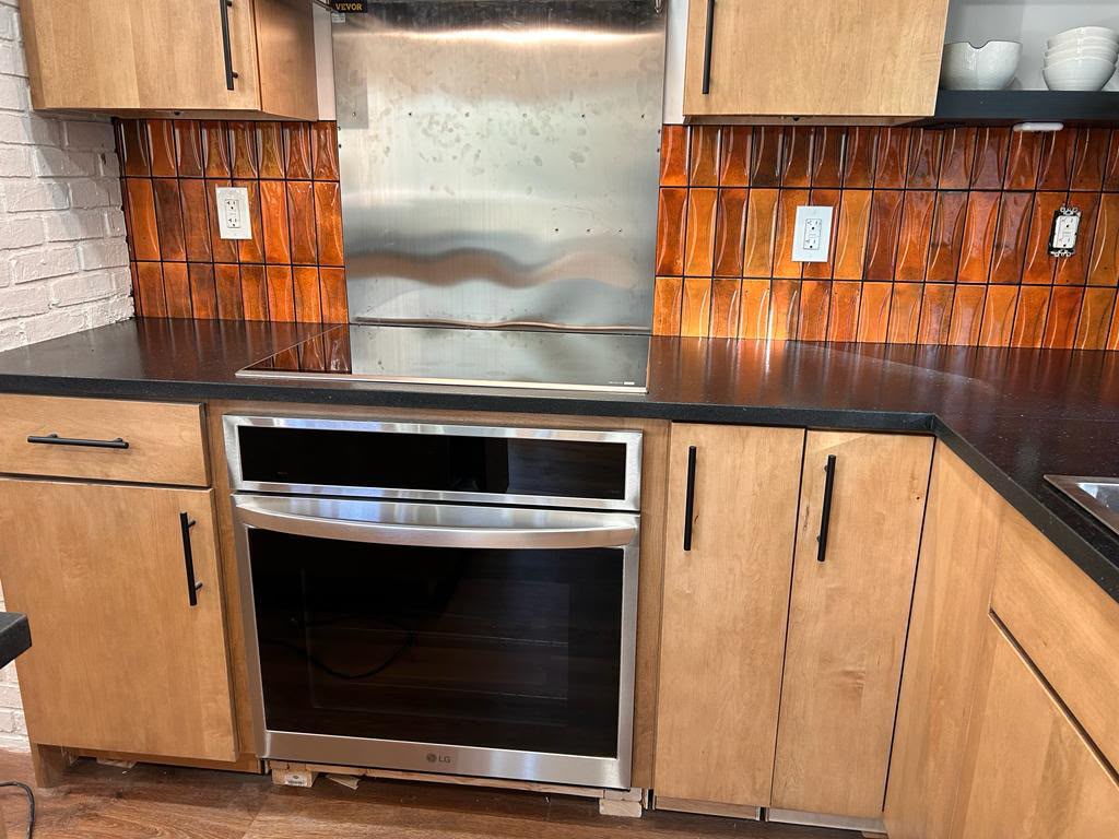Black countertop and terracotta backsplash finished in Mount Kisco