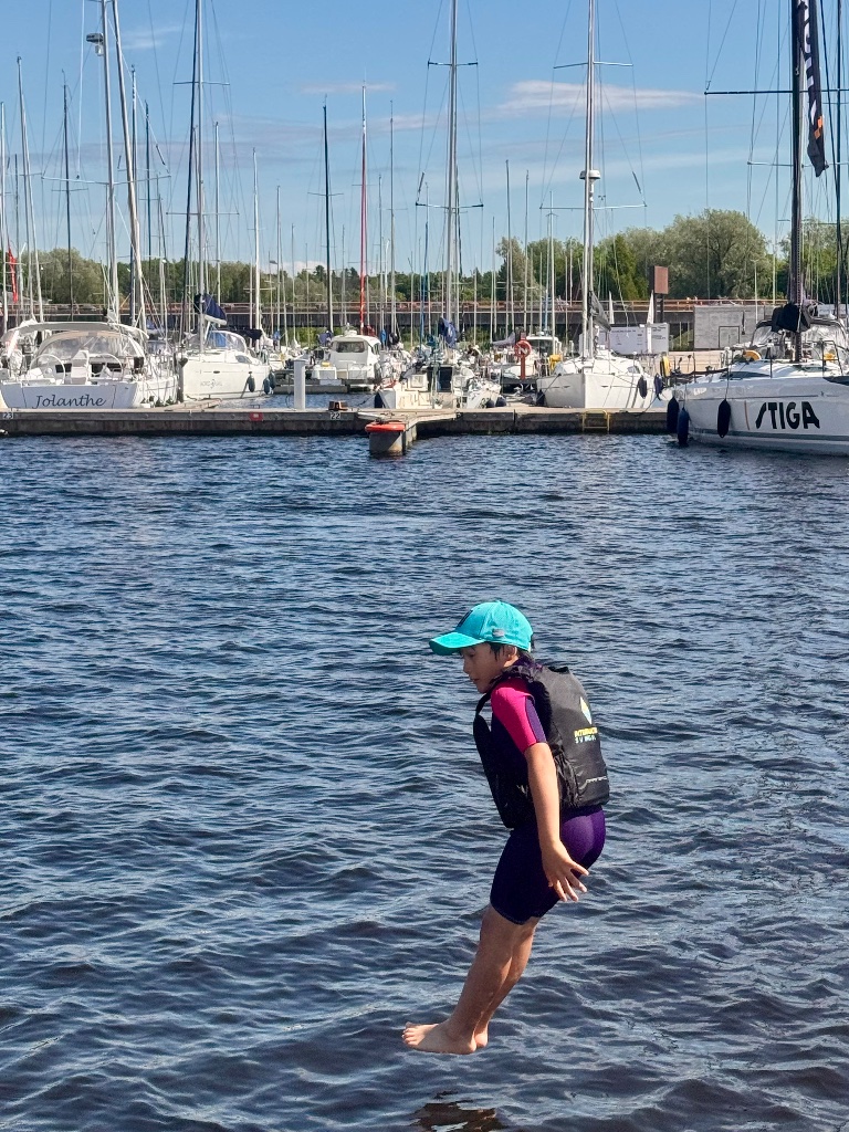 Child wading in Pirita harbour sailing camp