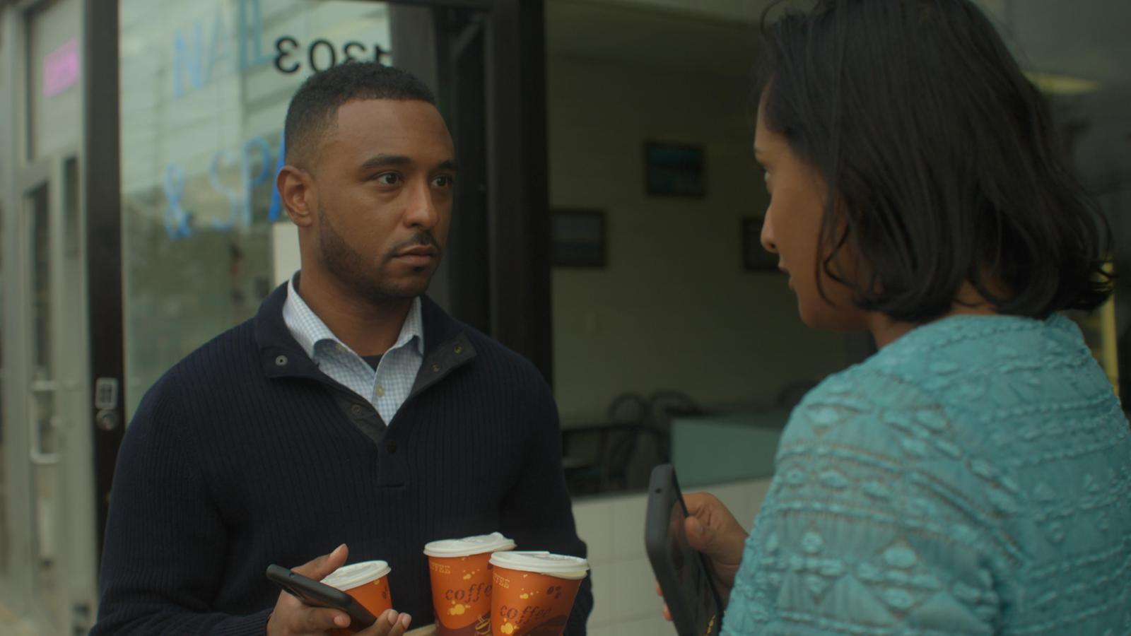 Actors in conversation outside the More Than A Bagel storefront, scene still from the film Doctored