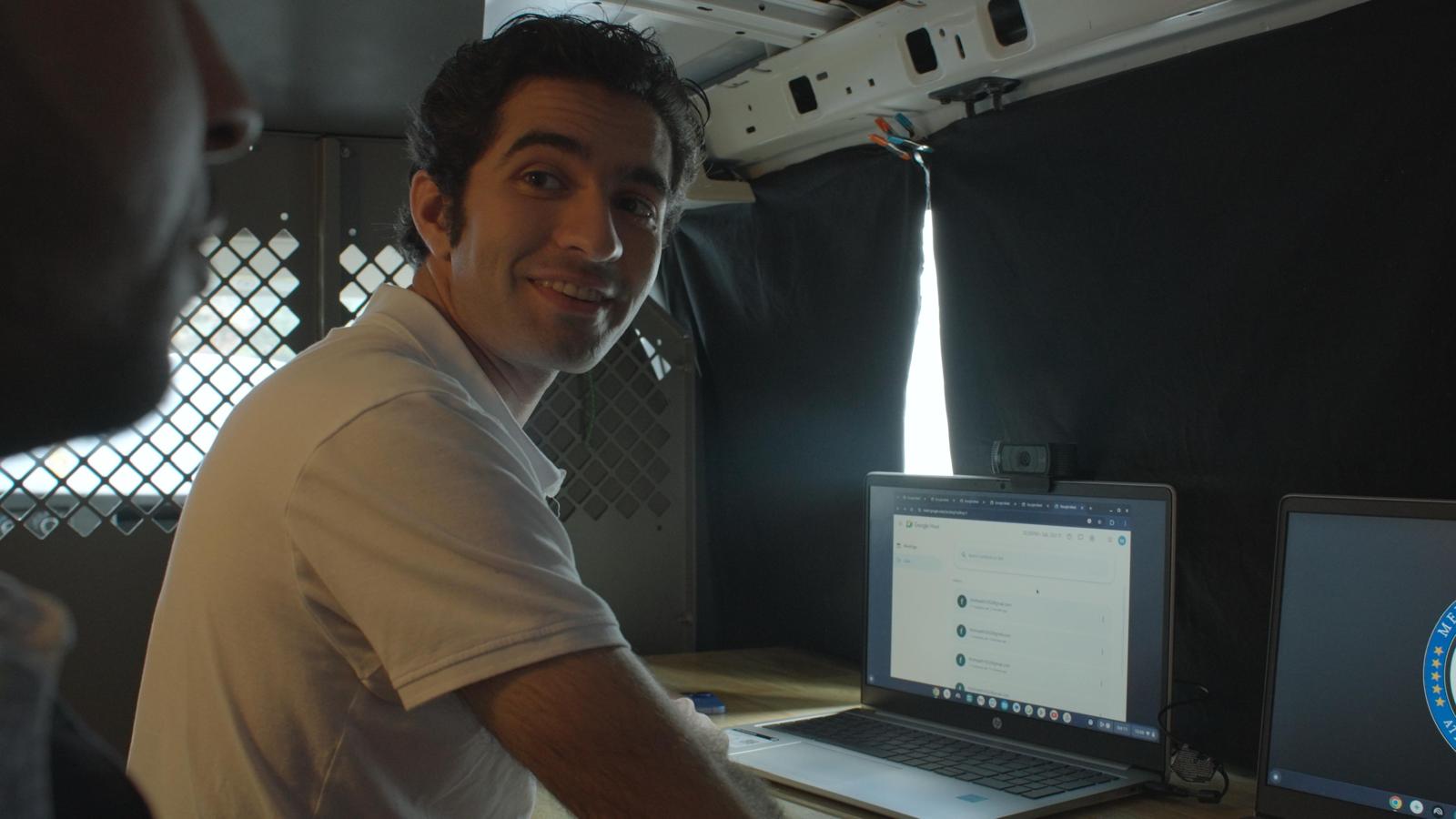 Actor smiling inside the production van on the set of Doctored, featuring laptop setup