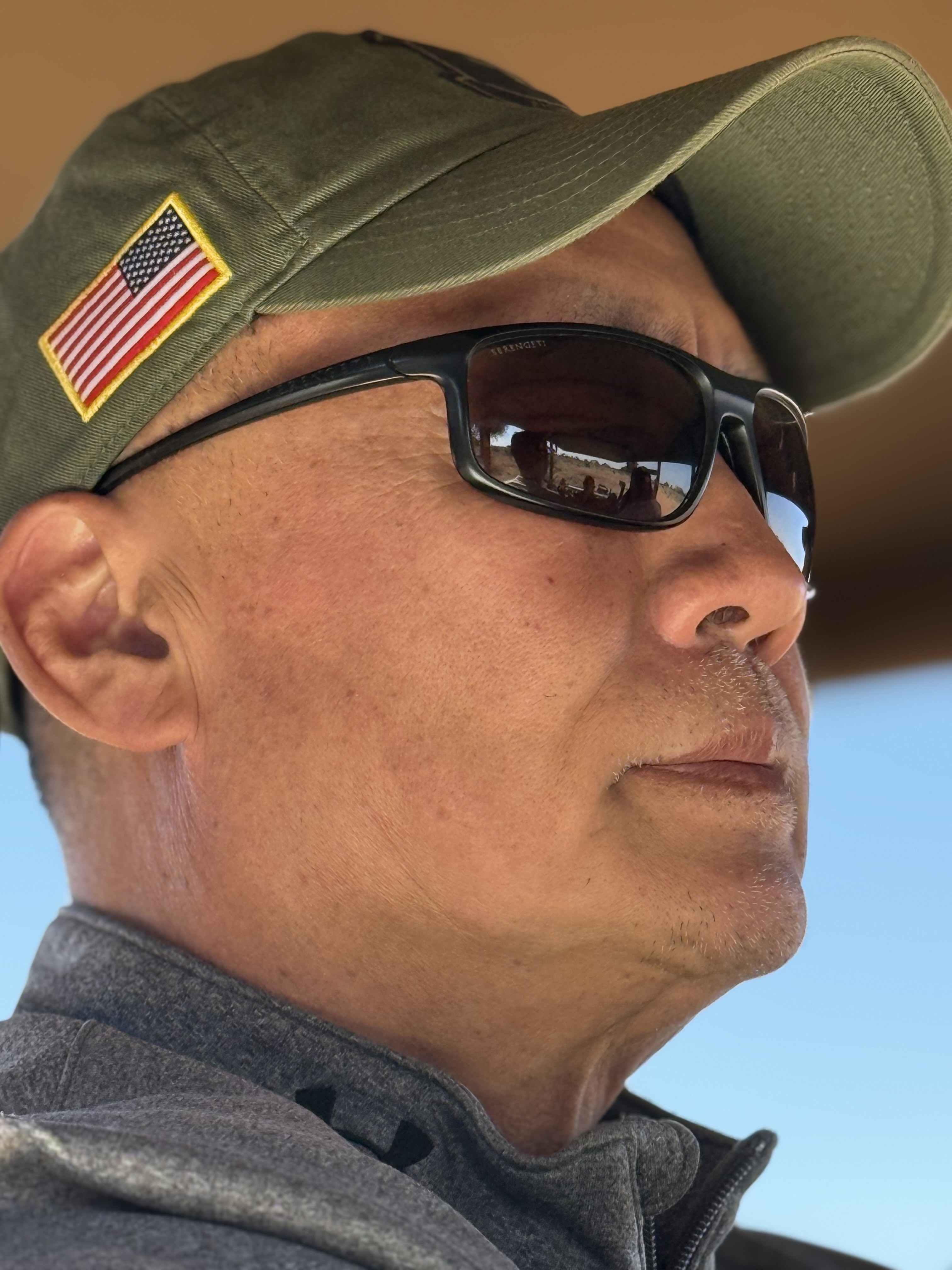 Veteran in profile on the safari vehicle, American flag on his cap