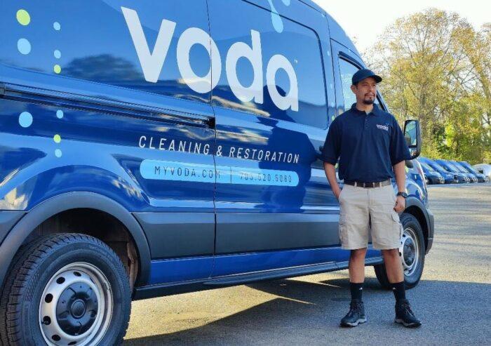 Voda Cleaning & Restoration technician standing next to the Voda van