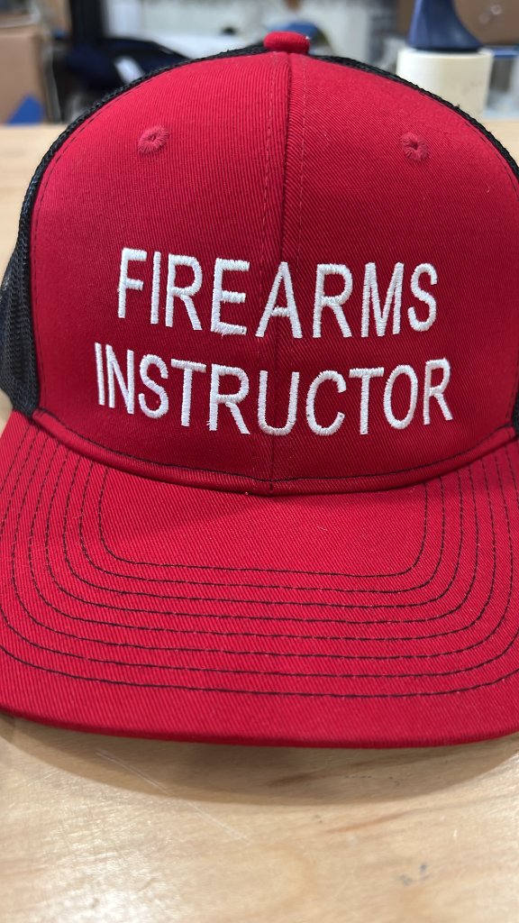 Firearms Instructor text embroidered on a red and black cap by Sew Suite