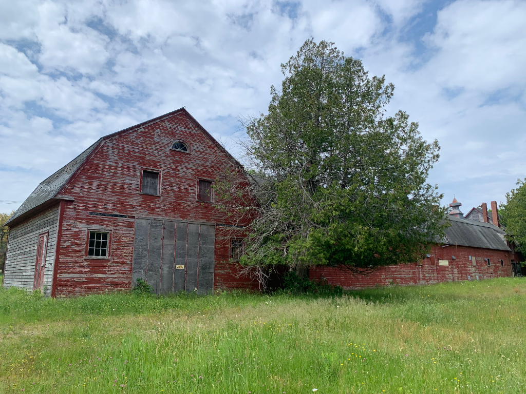 Full exterior side view of the weathered red barn with cupolas — Hamilton Station