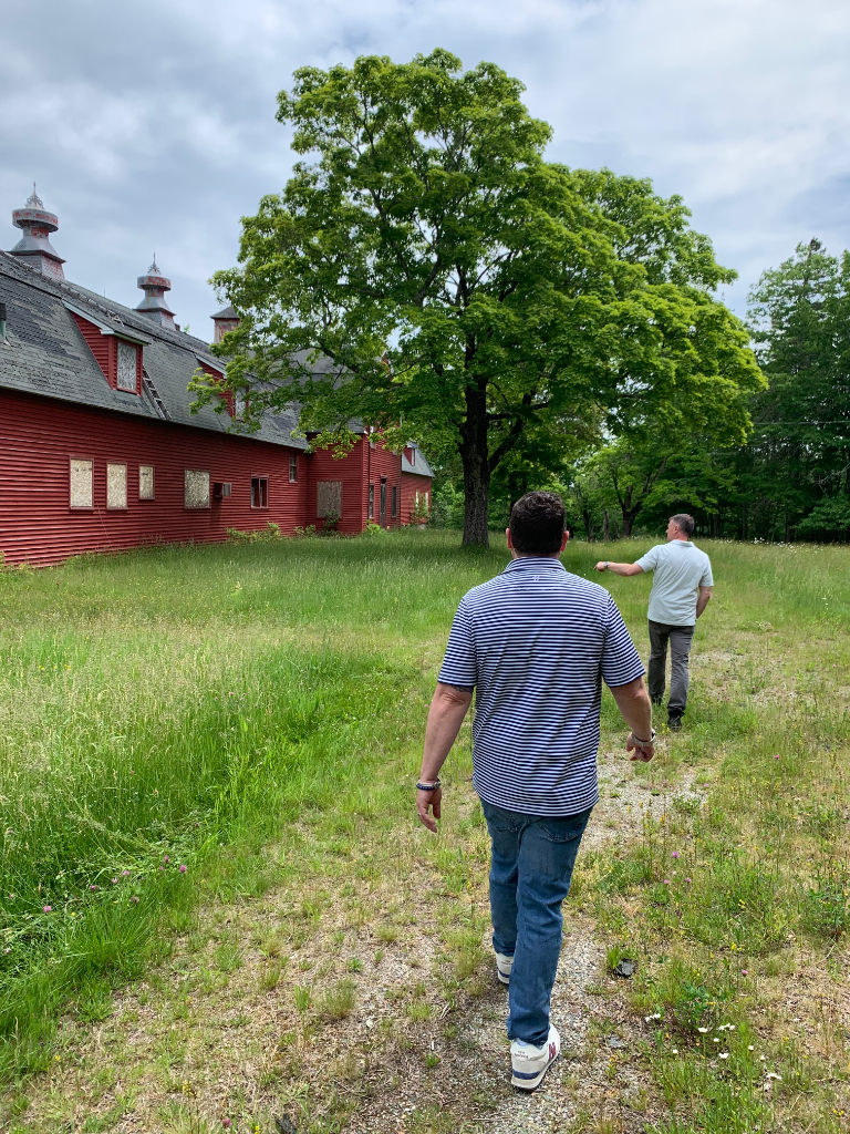 Two reviewers approaching the red barn along a gravel path
