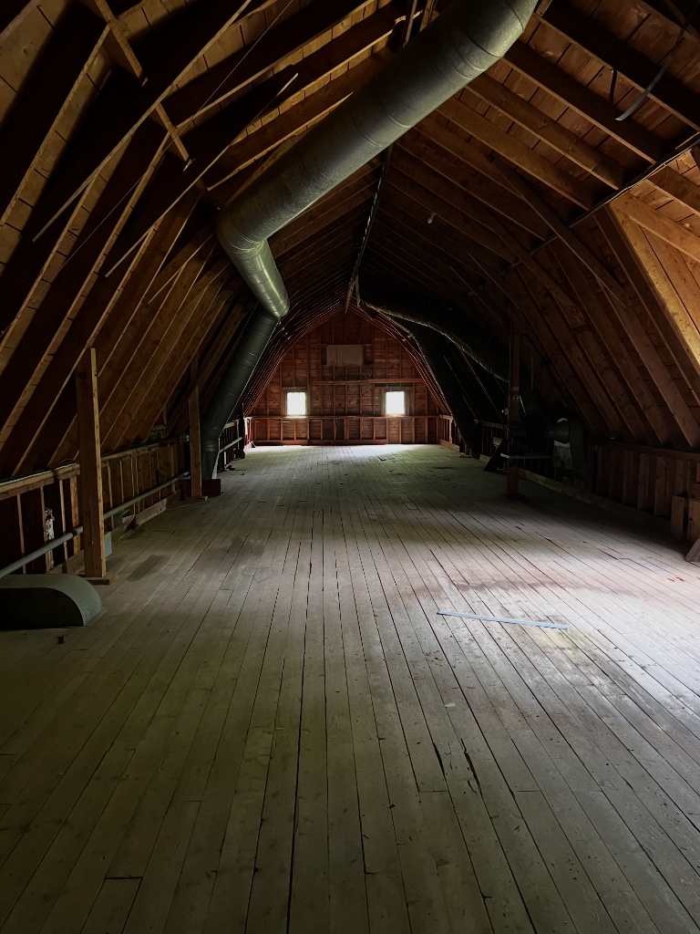 Interior timber framing of the Hamilton Station barn — wide plank floors and soaring roof structure