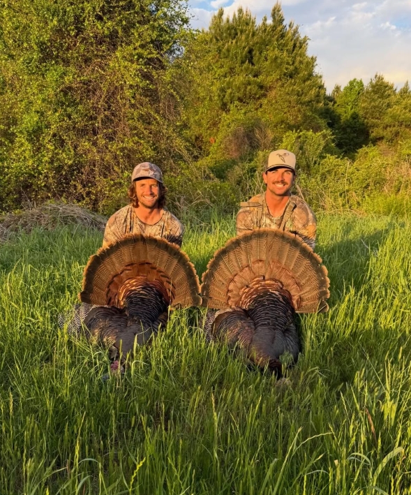 Two hunters with wild turkeys in an Outer Banks field