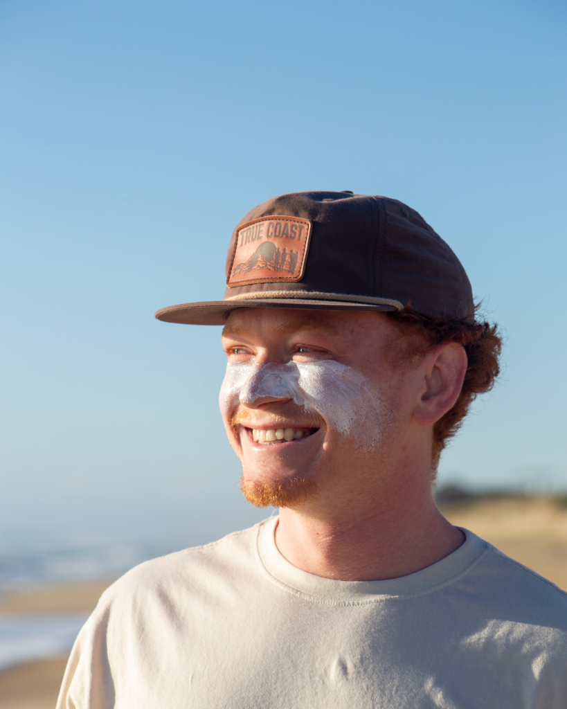Man with True Coast cap on beach
