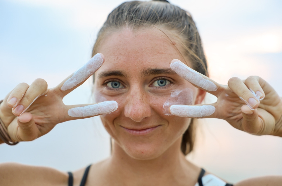 Woman with sunscreen on fingers in peace signs
