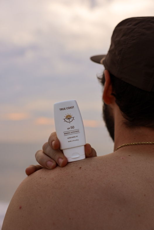 True Coast sunscreen tube on shoulder