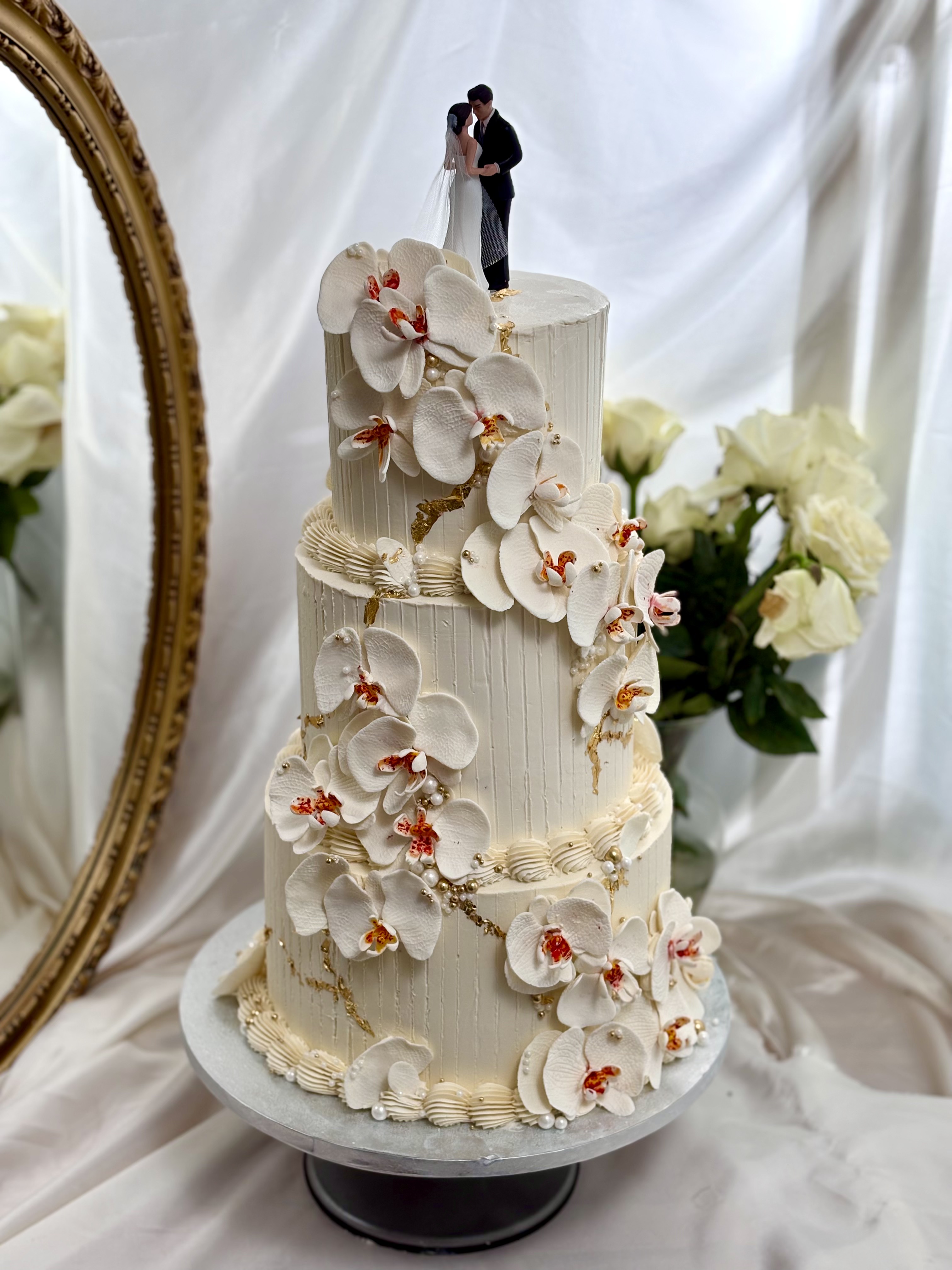 Gâteau de mariage trois étages orchidées en sucre feuilles d'or et topper silhouette mariés — Délices Éthérés