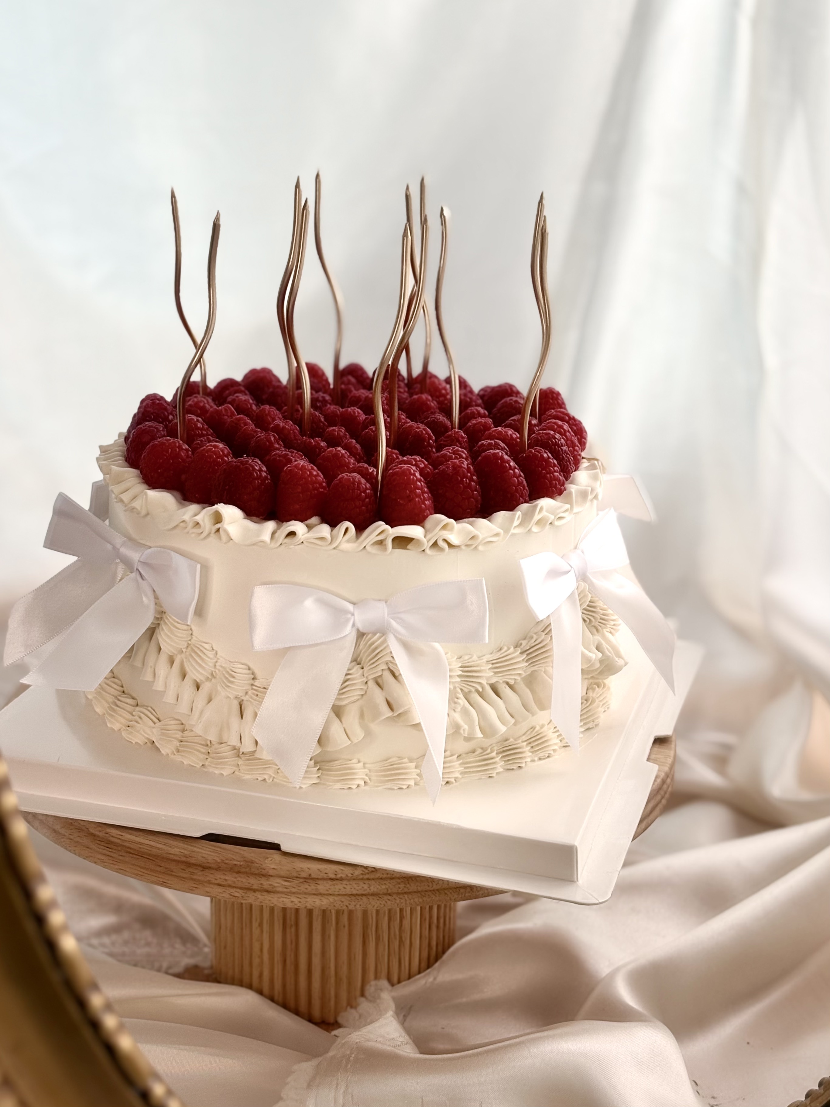 Gâteau anniversaire framboises fraîches bougies dorées et nœuds satin — Délices Éthérés