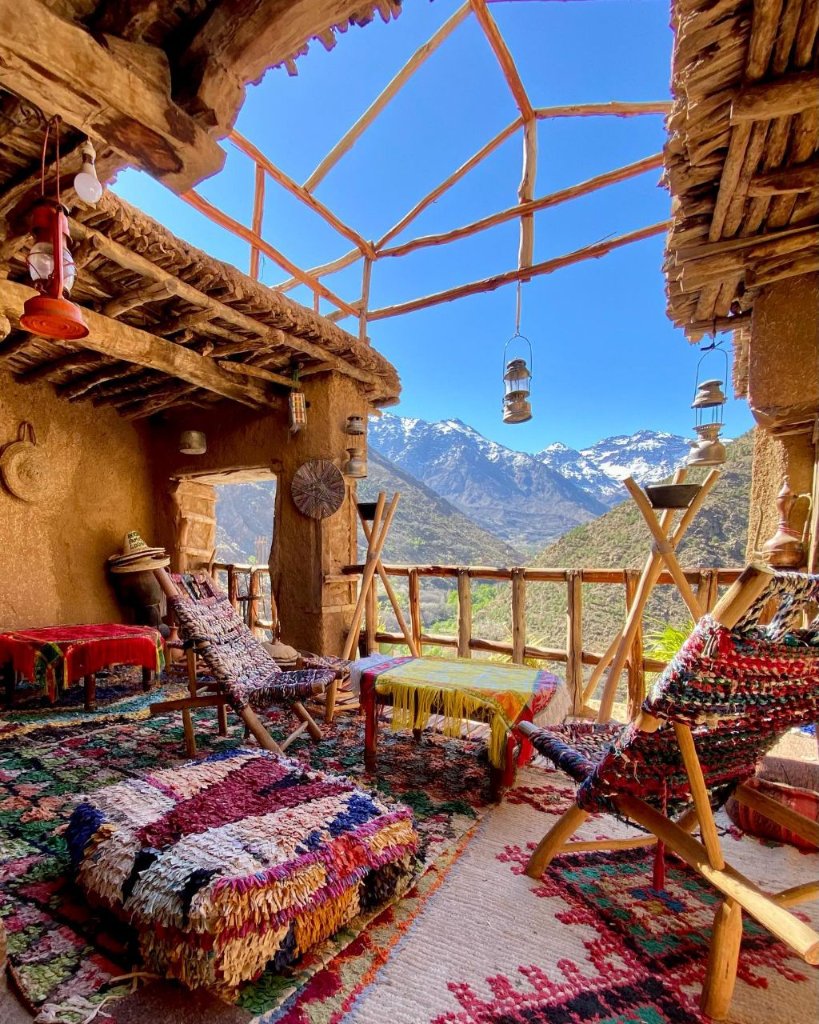 A traditional Amazigh terrace with woven carpets, low tables and lanterns overlooking the High Atlas
