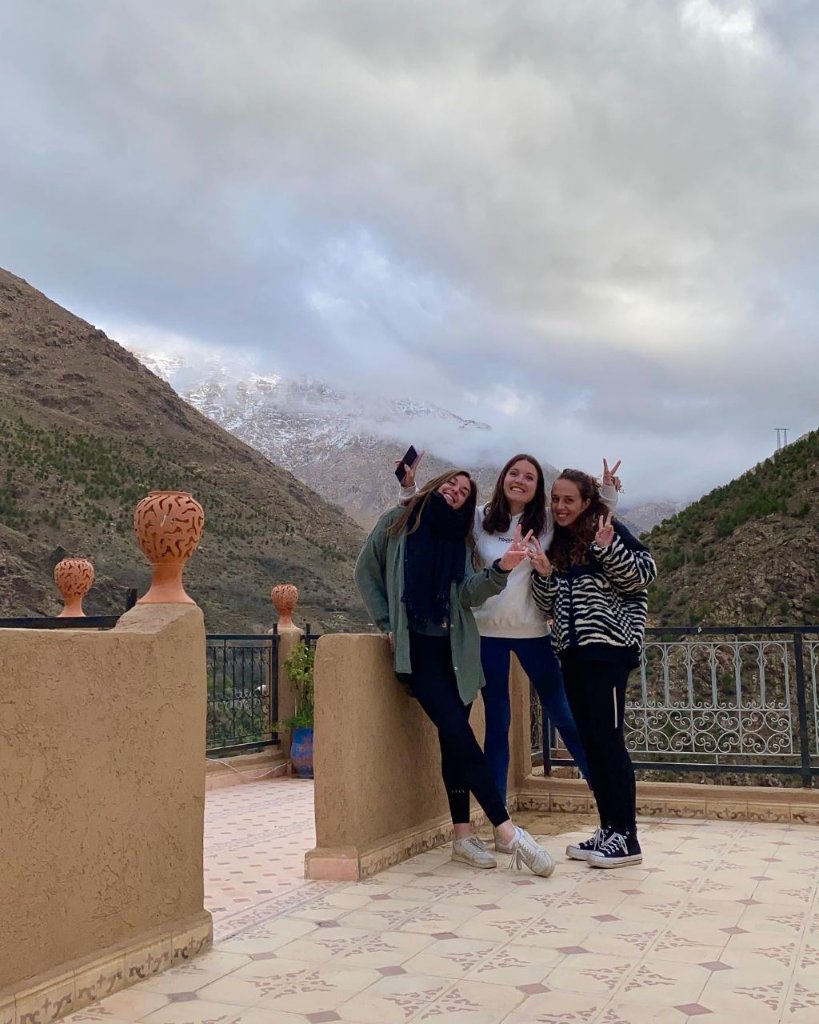 Three travellers smiling together on a rooftop terrace in Imlil during a small group day trip